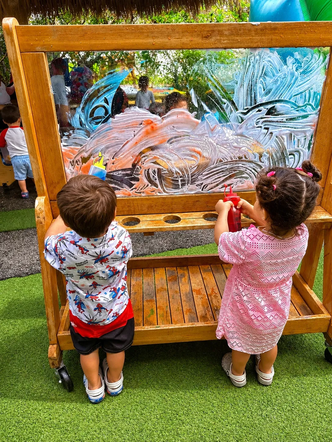 Children painting on a light panel outdoors at Creativa Academy
